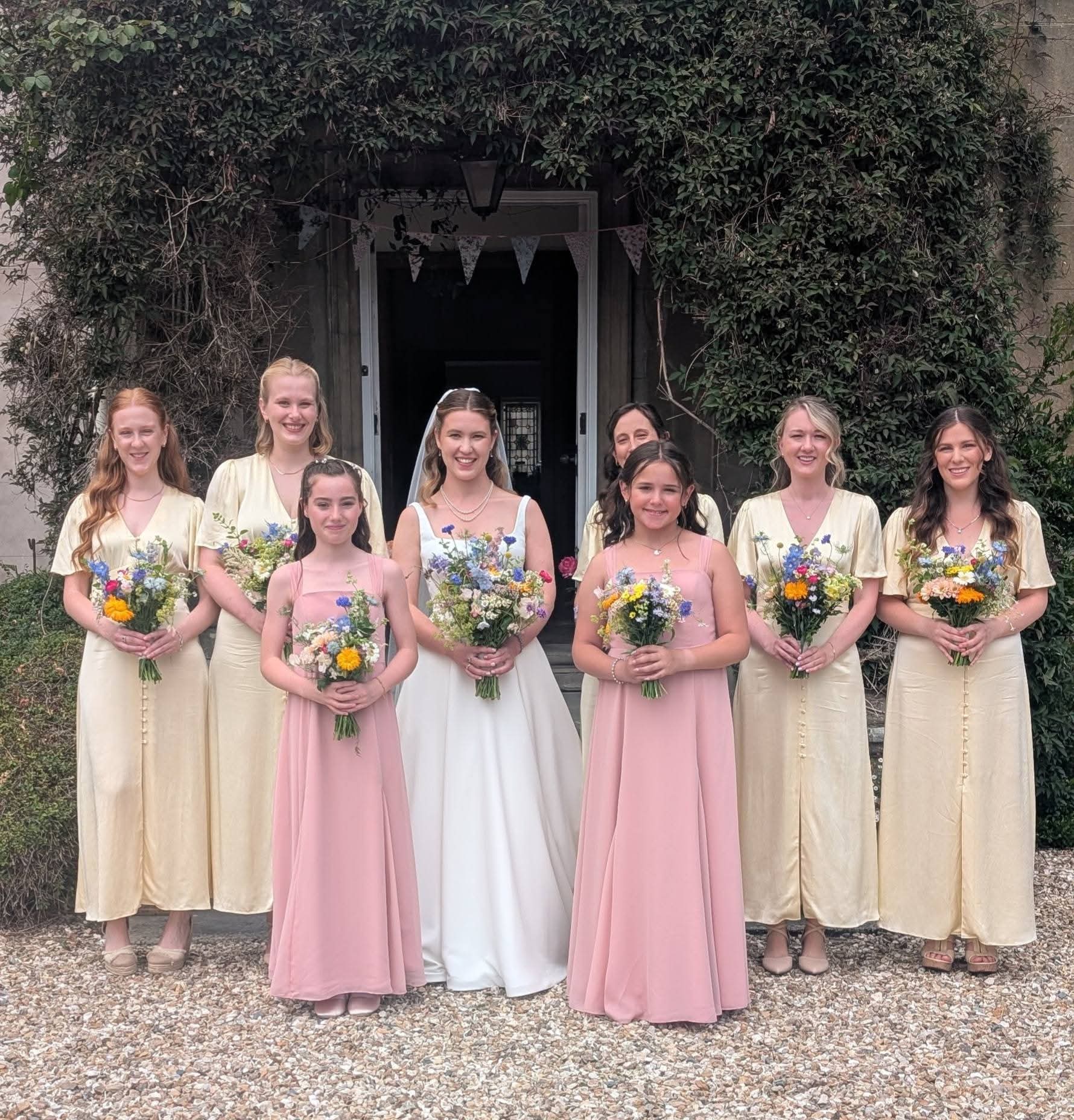 Bride with her bridesmaids in pastel dresses, all styled for the wedding day