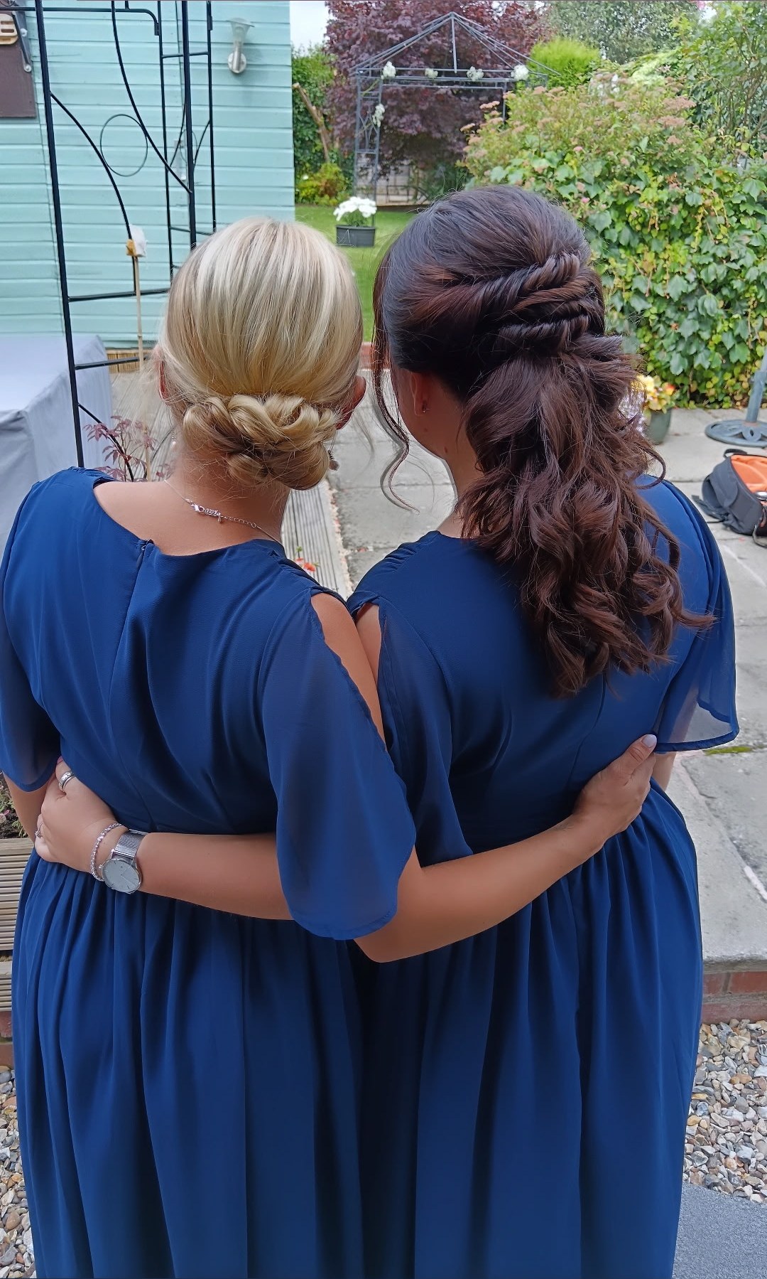 Two bridesmaids in navy with a braided bun and a curled half-up style