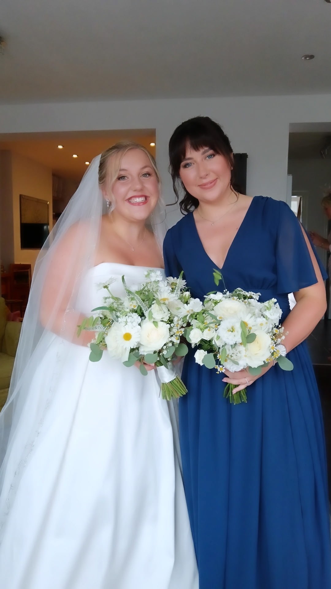 Bride and bridesmaid with wedding-morning hair, holding white bouquets
