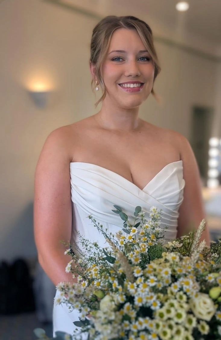 Bride with a softly dressed updo holding a wildflower bouquet on her wedding morning