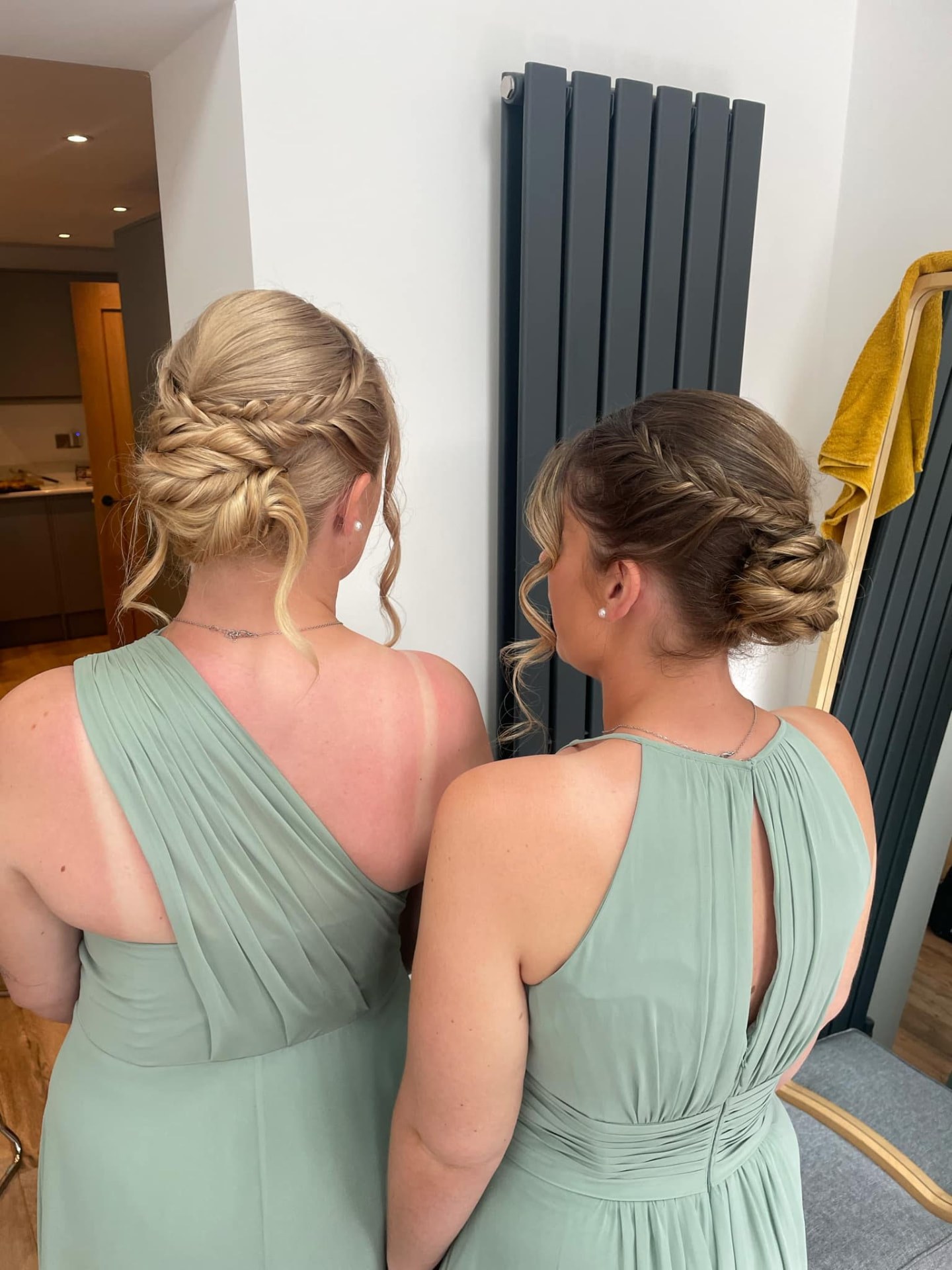 Two bridesmaids in sage green with fishtail-braided updos